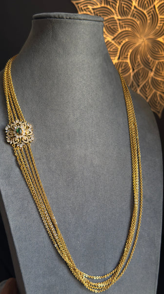 Gold necklace on a gray mannequin bust with a decorative background