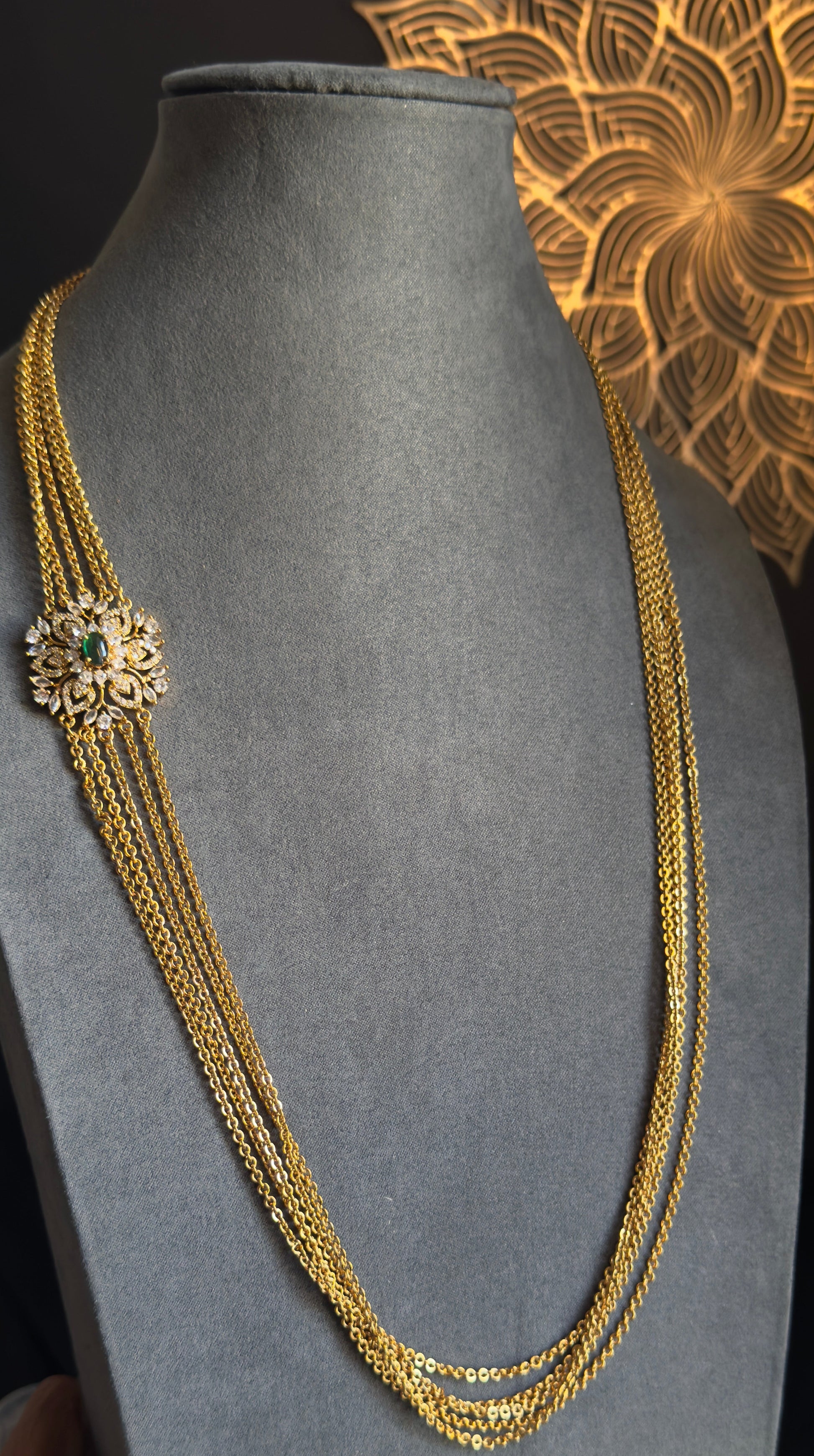 Gold necklace on a gray mannequin bust with a decorative background