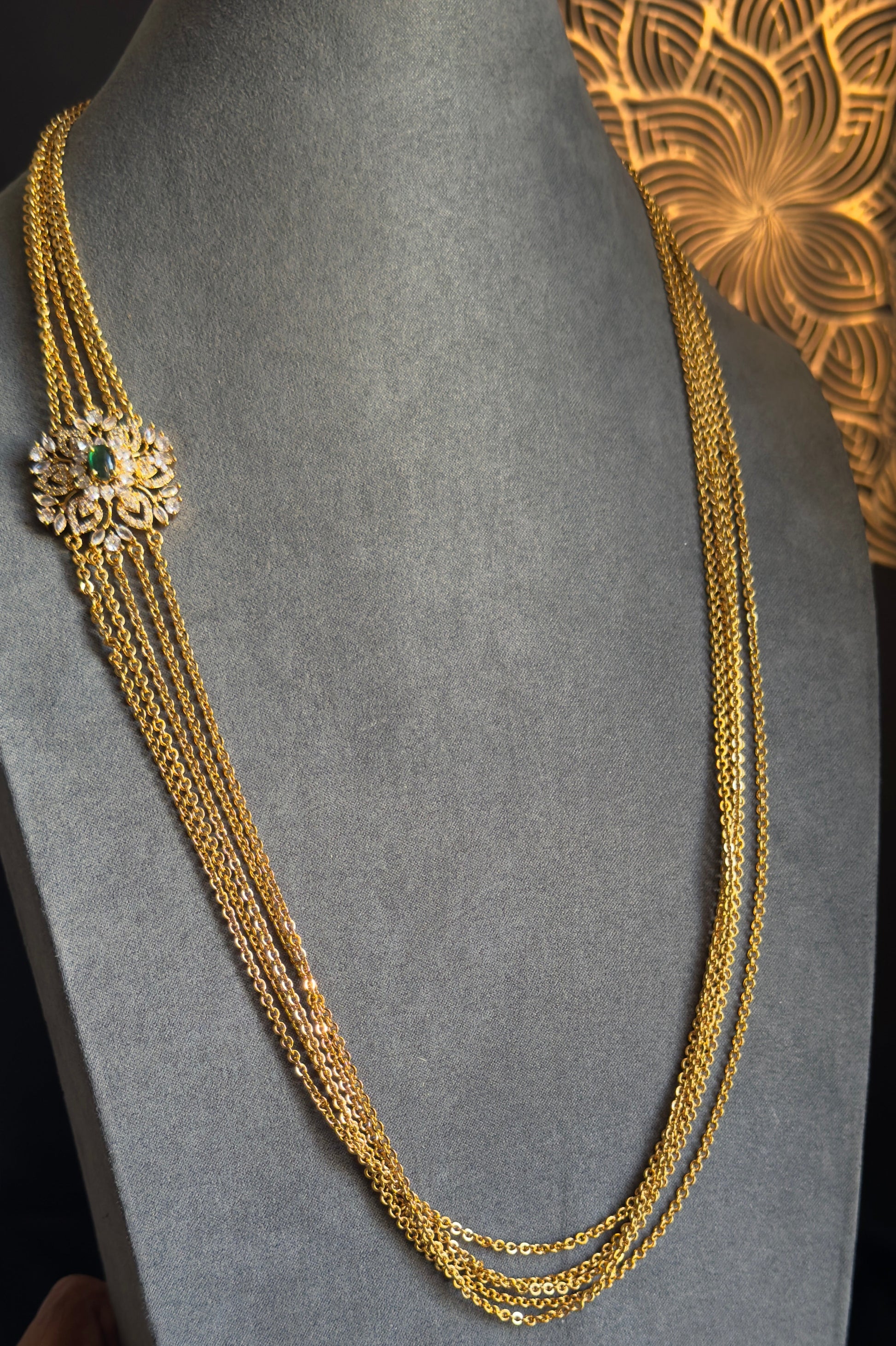 Gold necklace on a gray mannequin with a decorative background