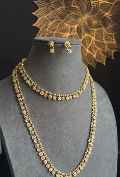 Gold necklace and earrings on a mannequin bust with a decorative gold background.