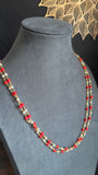 Necklace with red and gold beads on a gray mannequin bust against a black background.