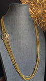 Gold necklace on a gray mannequin bust with a decorative background