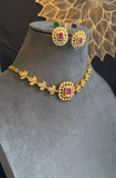 Gold necklace with red gemstones on a gray mannequin bust