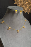 Gold necklace and earrings on a gray mannequin bust with a decorative background.