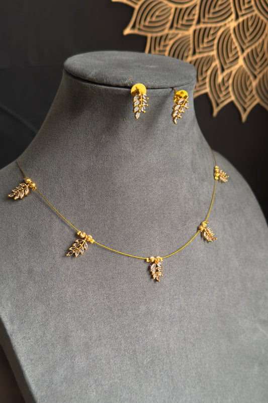 Gold necklace and earrings on a gray mannequin bust with a decorative background.