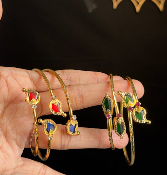 Gold bangles with colorful stones on a hand against a black background