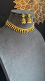 Gold necklace and earrings on a mannequin bust with a decorative background