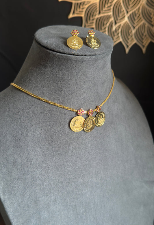 Gold necklace and earrings on a gray mannequin with a decorative background