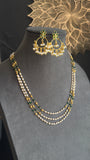 A three-layered pearl and bead necklace set with matching gold-toned earrings, displayed on a gray jewelry bust against a dark background with a decorative mandala motif.