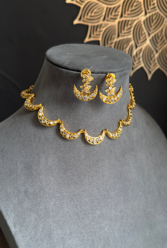 Gold necklace and earrings on a gray mannequin with a dark background