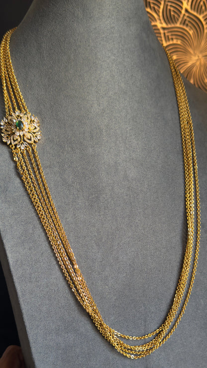 Gold necklace on a gray mannequin with a decorative background