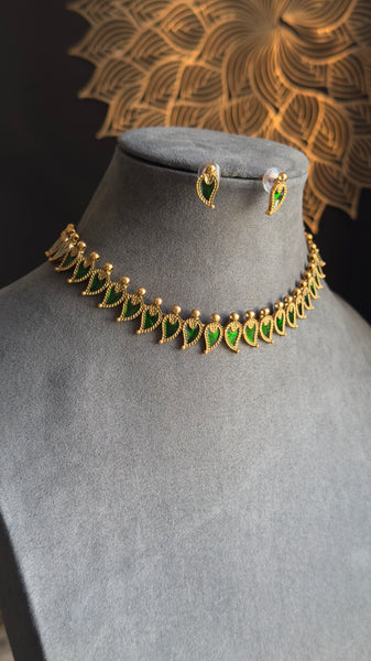 Gold necklace with green stones on a mannequin bust against a decorative gold background