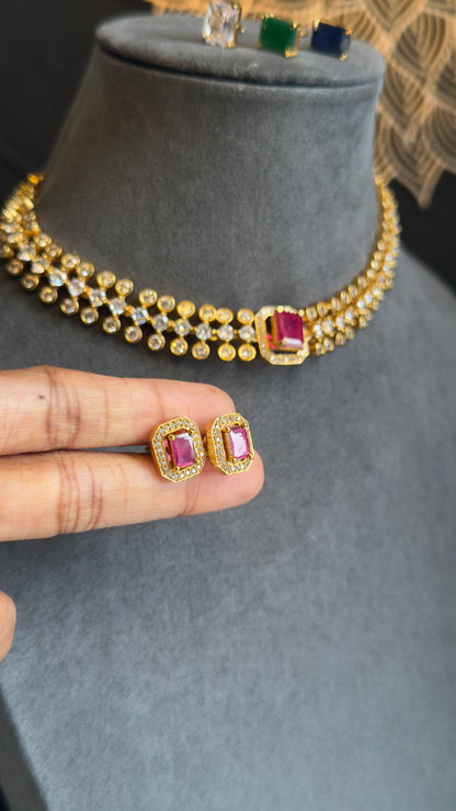Gold necklace with red gemstones on a gray stand, held by a hand.