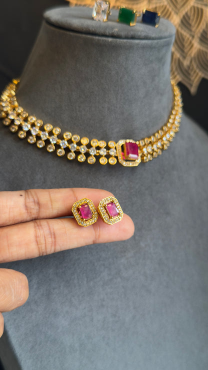 Gold necklace with pink gemstones on a gray stand, held by a hand.