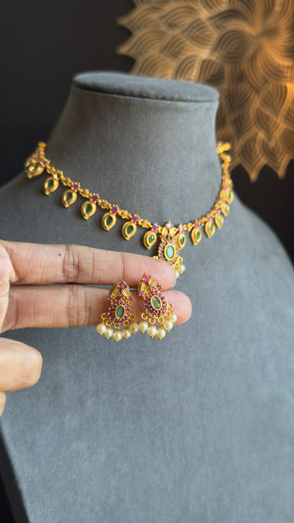 Gold necklace and earrings on a mannequin bust with a hand holding the earrings.
