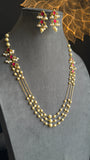 Pearl necklace with red stones on a gray mannequin with a decorative background