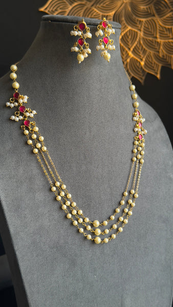 Pearl necklace with red stones on a gray mannequin with a decorative background