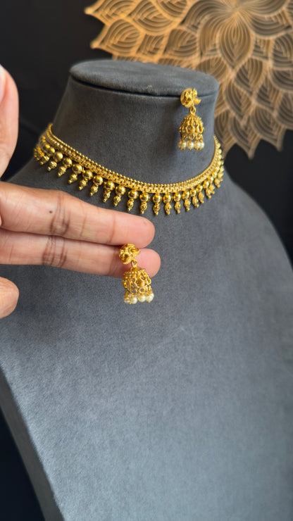 Gold necklace with matching earrings on a gray mannequin bust.