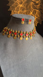 Traditional gold necklace with red stones and matching earrings on a mannequin head.