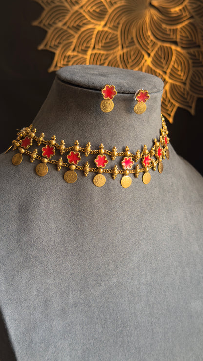 Traditional gold necklace with red stones and matching earrings on a mannequin head.