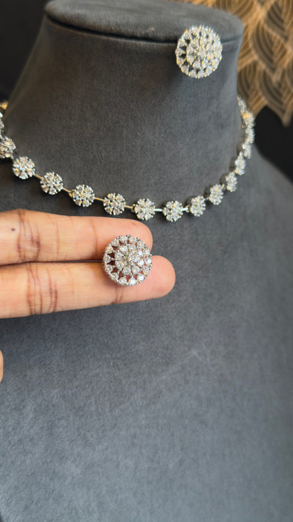 Silver necklace and earrings on a mannequin bust with a hand holding one earring.